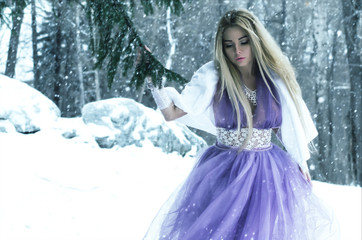 beautiful blonde girl in a chic lilac dress in the winter forest