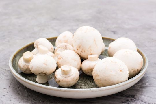 Fresh mushrooms in a plate on a concrete table