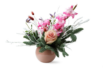 Winter composition in a brown pot - spruce branches, pink gladiolus, cream rose, dried flower spikelets and twigs covered with artificial snow - on white background