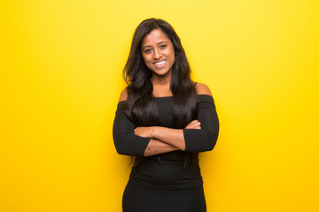 Young afro american woman on vibrant yellow background keeping the arms crossed in frontal position