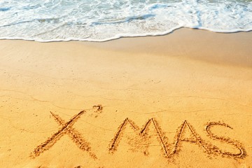 Happy new year concept, Xmas handwriting on sand beach.