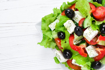 Greek salad on a white wooden background. Space for text or design.