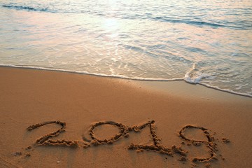 Happy new year concept, 2019 handwriting on sand beach.