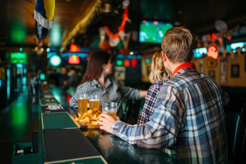 Naklejka premium Fans with glasses of beer at counter in sports bar