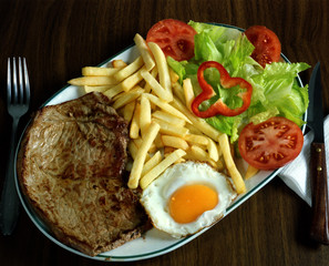 Plato combinado con un biftec, un huevo frito, patatas fritas y ensalada