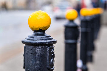 yellow metal ball on street post, blurred city street