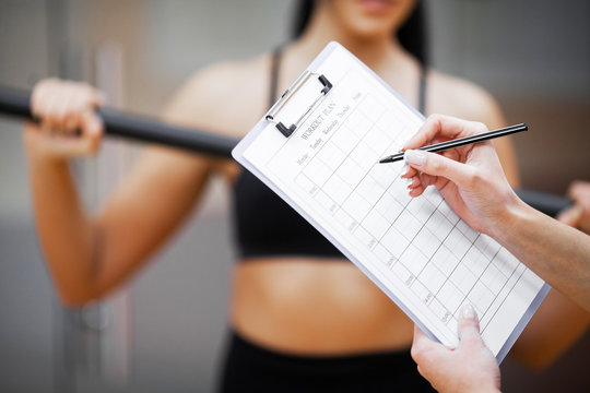 Fitness plan. Sports trainer amounts to workout plan close-up