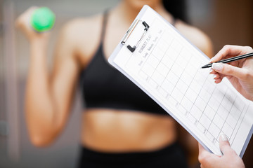 Fitness plan. Sports trainer amounts to workout plan close-up