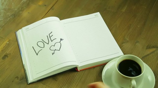 The girl writes the word love in the diary. Time laps.