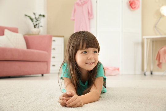 Cute little girl lying on carpet at home