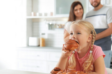 Little girl eating freshly oven baked bun in kitchen. Space for text