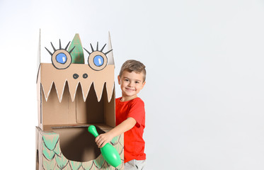 Cute little boy playing with cardboard dragon on white background. Space for text