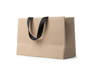 Paper shopping bag with ribbon handles on white background. Mockup for design