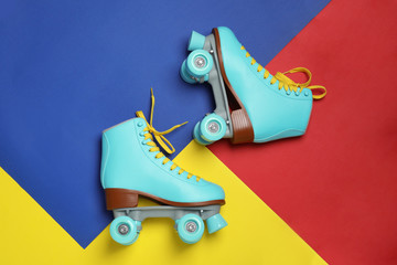 Pair of stylish quad roller skates on color background, top view