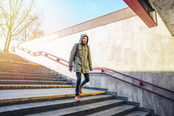 Tourist man in a hood goes down into the underpass in an urban environment. Tourist in winter city concept