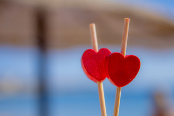 Red hearts as a gift for Valentine's Day.Heart is fall love. Sea beach umbrella Valentine day background with two love hearts