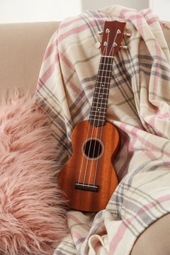 Brown wooden guitar on sofa at home