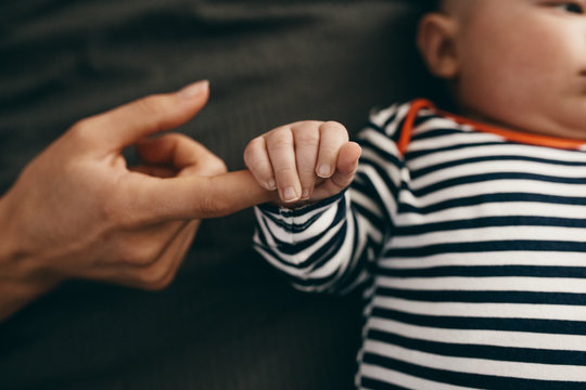Close up of a baby holding the hand of his mother