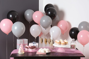 Party treats and items on table in room decorated with balloons