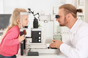 Fototapeta na wymiar Children's doctor examining little girl with ophthalmic equipment in clinic