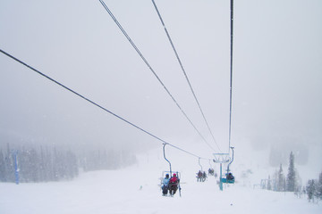 Fototapeta na wymiar ski resort in a snowstorm; winter; skiers on chairlift