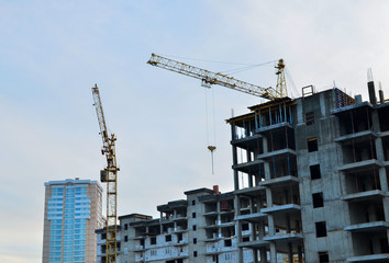 Building construction site with crane against bright blue sky. Construction of new high-rise from concrette and steel.