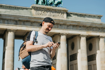 A tourist or a guy with a backpack uses a mobile phone to call or see a map or get online.