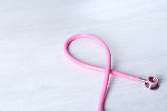 Pink stethoscope as awareness ribbon on light background. Breast cancer concept