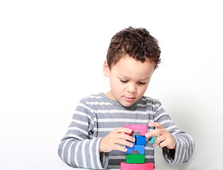 little boy testing his creativity by building towers with toy building blocks