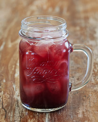 Cherry lemonade in a cup on a wooden background
