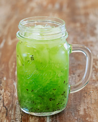 Kiwi lemonade in a cup on a wooden background