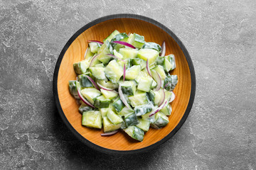 Wooden dish with fresh creamy cucumber salad on table, top view