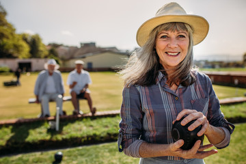 Close up of a woman playing boules in a lawn