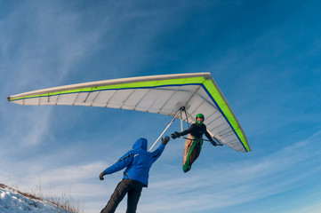 Man on the ground and hang glider pilot in the air shake hands.