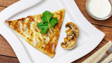 Pancakes with meat and mushrooms on a wooden background, top view