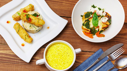 Set of business lunch, soup, salad and dish with meat in a plate on a wooden background, top view