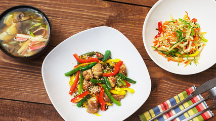 Set of business lunch, soup, salad and dish with meat in a plate on a wooden background, top view