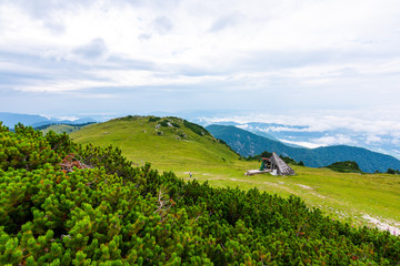 Panoramatic view to Slovenia Alps near city Kamnik. Big plateau with pasture and wooden houses. Landscape with green grass and clouds above the hill.