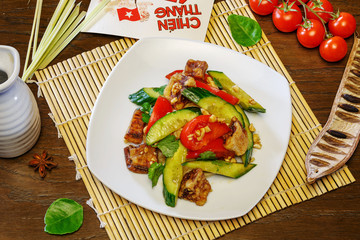 Vegetable salad in a plate on a wooden background, top view