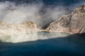 Turquoise lake in active crater volcano with smoke