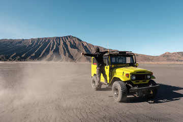 Tourist man thumb a lift on yellow four wheel car in desert
