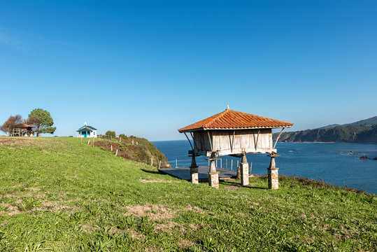 Typical granary (horreo) and the chapel of La Regalina in Cadavedo, Asturias, Spain