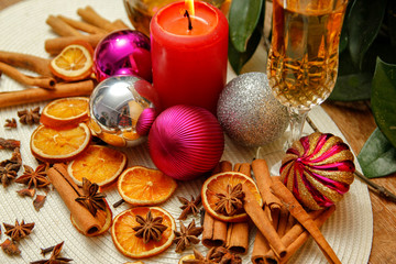 Holiday Christmas decoration with white wine, Christmas ball, candle, dried orange, anise stars and sticks of cinnamon. Wooden table and vintage background.
