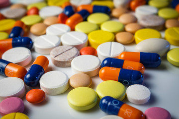 Many capsules and pills on a white plate