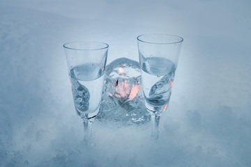 Two vodka shots with burning tealight in snow front view 