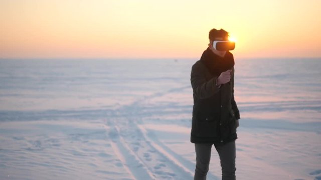 A man wearing glasses of virtual reality is walking in the winter outside