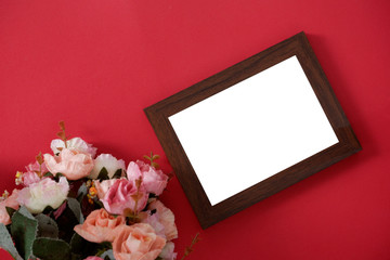 Mock-up wooden photo frame with space for text or picture on red background and flower.