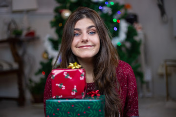 Portrait of young woman with blue eyes holding christmas gifts