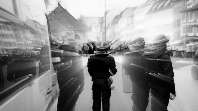 Visual effects over unrecognizable Police officers securing the zone in front of protesters demonstration center character emitting light - black and white 4k footage