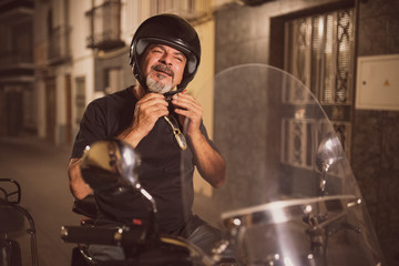 Senior biker adjusting helmet ready for travel on bike
